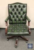 A green buttoned leather office armchair, width 64 cm.