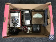 A box containing vintage voltmeters and ammeters
