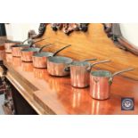 A graduated set of seven Victorian copper pans with iron handles,