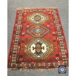A Caucasian design rug on red ground, 186 cm x 122 cm.