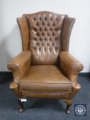 A brown button leather wing back armchair