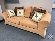 A contemporary settee upholstered in orange fabric with loose scatter cushions
