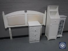 A white headboard, three drawer chest,
