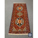 A Persian fringed rug on red ground,