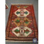 A Persian fringed rug on red ground,
