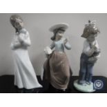 Three Nao figurines ; girl with puppy, girl with doll and basket of flowers.