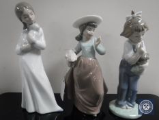 Three Nao figurines ; girl with puppy, girl with doll and basket of flowers.