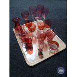 A tray of antique and later cranberry glass ware, jugs, vases, wine glasses etc.