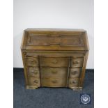 A continental oak serpentine fronted three drawer bureau