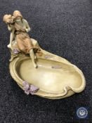 A continental porcelain shallow dish surmounted by two figures,