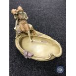 A continental porcelain shallow dish surmounted by two figures,