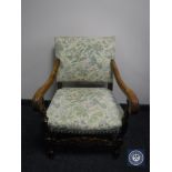 A 20th century carved oak scroll arm armchair in floral fabric