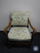 A 20th century carved oak scroll arm armchair in floral fabric