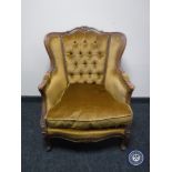 A 20th century carved wood framed armchair in gold button fabric