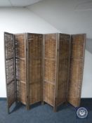 A wood and wicker six-way folding room divider