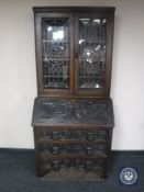 A Victorian carved oak Green Man bureau bookcase with leaded glass doors