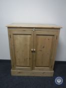 A stripped pine double door cabinet