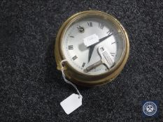 A circular brass ship's clock with key