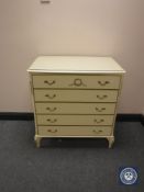 A cream and gilt glass topped five drawer chest and pair of matching bedside stands
