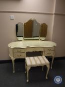 A cream and gilt kidney shaped dressing table with mirror and stool