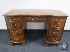 A mahogany serpentine fronted knee hole writing desk fitted nine drawers