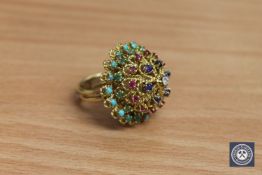 A high carat gold multi-gemstone ring, set with tiers of turquoise, emeralds, rubies,