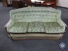 A mid 20th century shaped three seater settee in green brocade