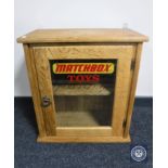 A blonde oak single door wall cabinet with "Matchbox Toys" advertising