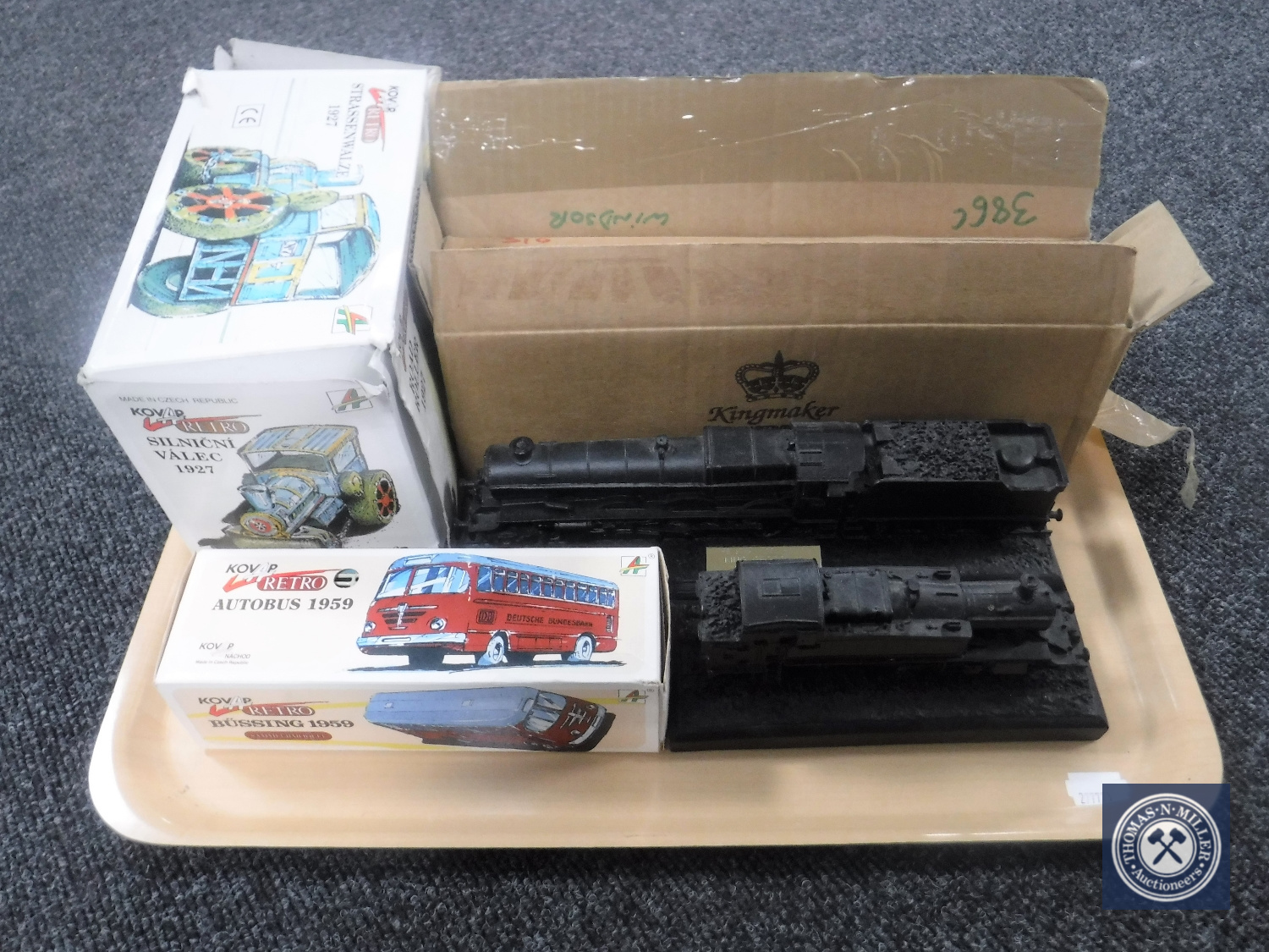 A tray containing four Kingmaker scale model trains together with a boxed Kovap retro bus and a