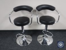 A pair of metal gas lift bar stools