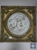 A gilt framed ceramic cherub relief plaque