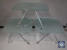 Three square glass topped coffee tables on metal legs