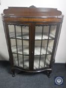 An early 20th century shaped front display cabinet on claw and ball feet