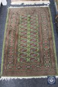 Lahore Bokhara rug, Pakistan, the olive green field of guls closed by sun burst motif borders,