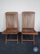 A pair of folding teak garden chairs