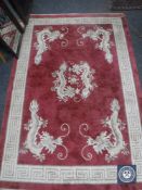 A fringed Chinese rug on pink ground, 140cm by 62cm, together with another on black ground,