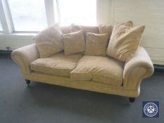 A pair of Barker & Stonehouse two-seater scroll arm settees in gold fabric with scatter cushions