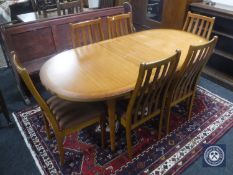 An oval teak Stateroom extending dining table and six rail back chairs