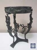 A patinated cast bronze vase stand raised on three legs with griffon supports