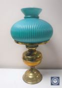 An early 20th century brass oil lamp with chimney and green glass shade