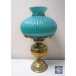 An early 20th century brass oil lamp with chimney and green glass shade