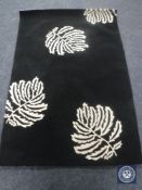 A hand tufted leaf design black rug, 120 cm x 180 cm, rrp £297.