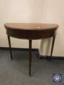 An Edwardian mahogany demi-lune card table with green baize interior, width 84 cm.