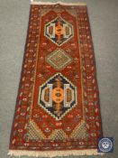 A fringed Caucasian design rug on red ground,