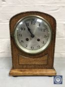 An oak cased mantel clock with silvered dial,