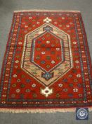 A fringed Caucasian design rug on red ground,