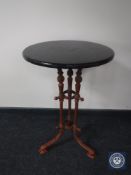 A circular wooden topped occasional table on a cast iron three-way support