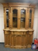 A heavily carved pine serpentine fronted glazed bookcase, width 155 cm.