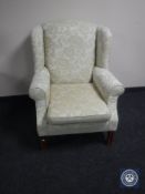 A wing back armchair in cream floral fabric