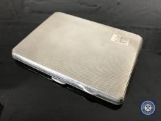 A silver cigarette case with engine turned decoration